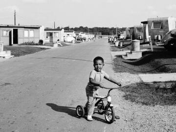 Un enfant sur son tricycle à la base militaire américaine d’Évreux. 1963. Crédits : Daniel Fallot.
